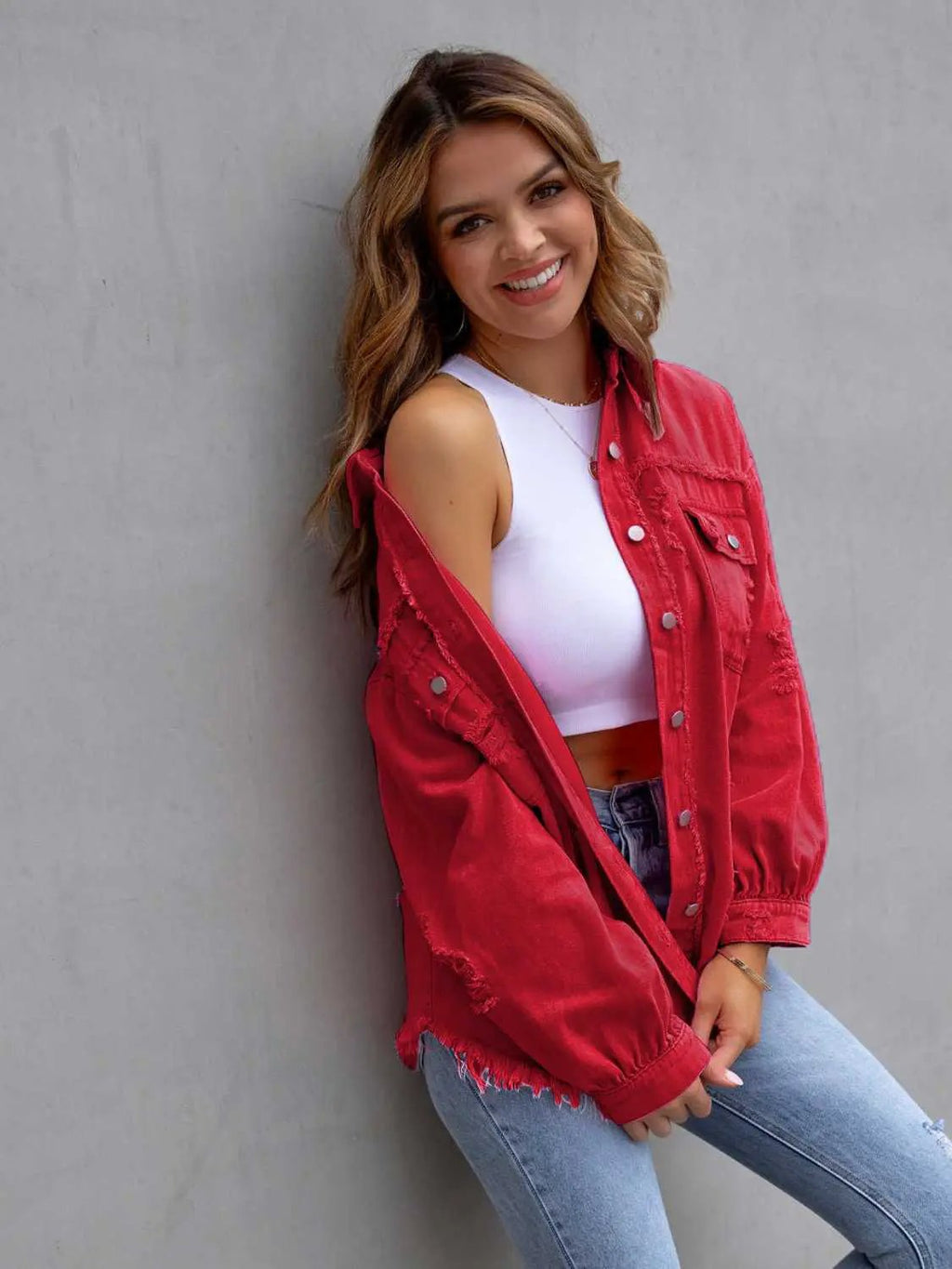 Distressed drop-shoulder red denim jacket on model wearing a white crop top