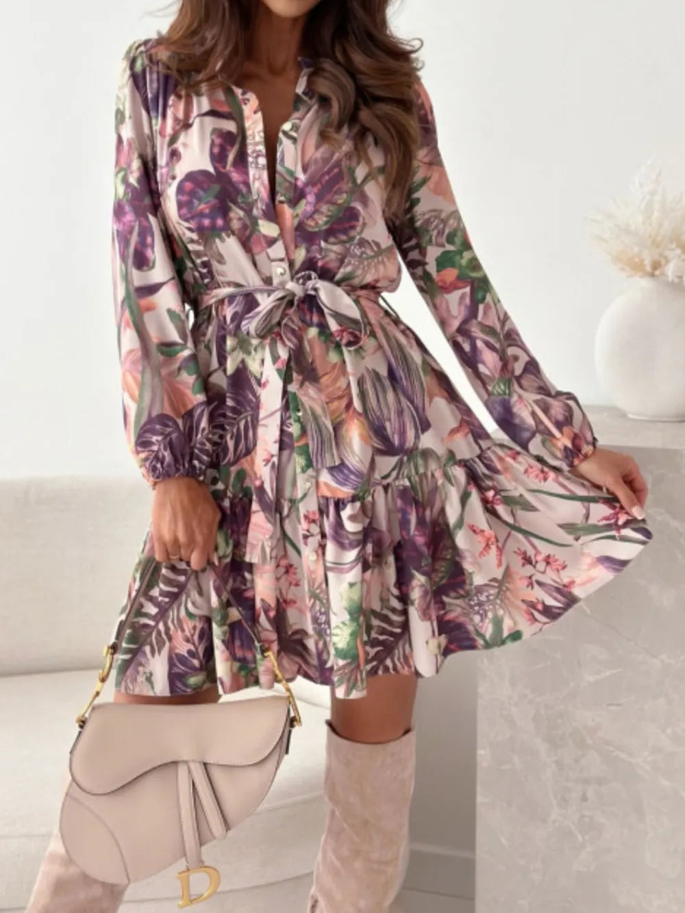Ruffle-hem floral long-sleeve dress by Belle Bijouix with waist tie and buttoned front in pink-purple print.