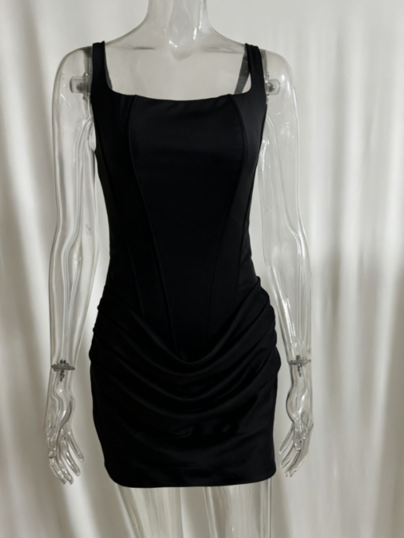 Ruched sleeveless black mini dress on a clear display mannequin