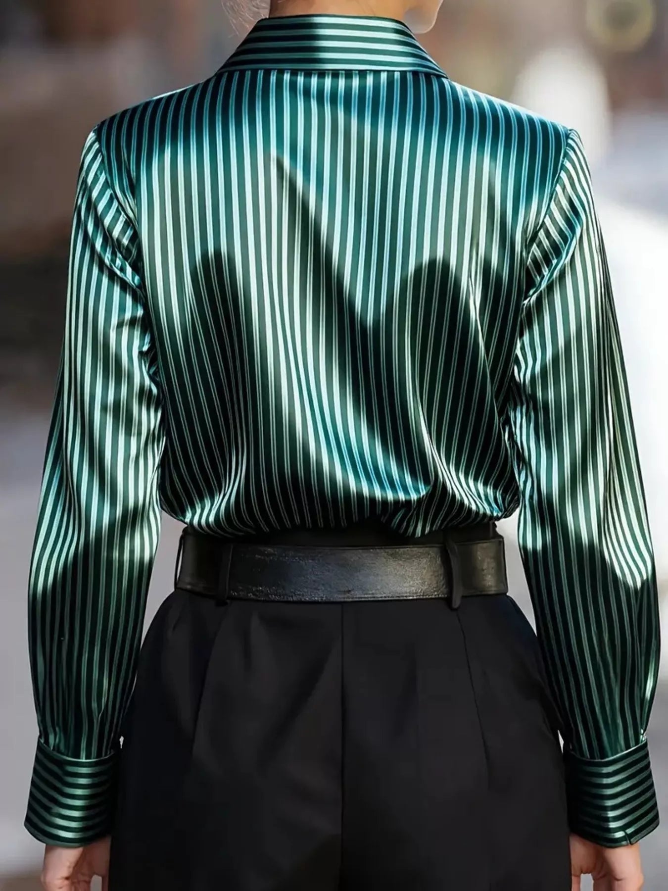 Striped green and white satin long-sleeve shirt, back view tucked into black belted pants