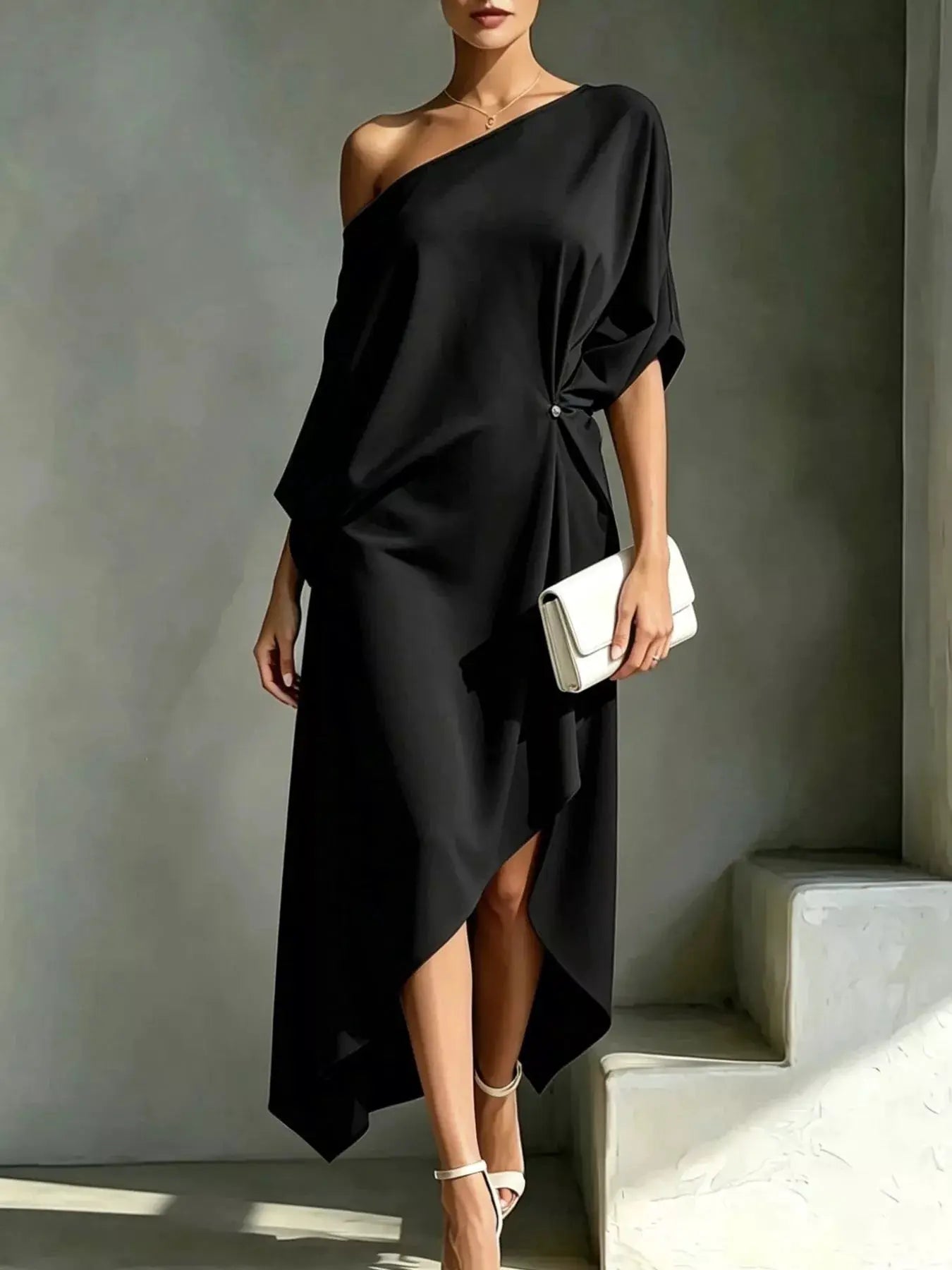 Plus size asymmetrical one-shoulder draped black dress with white clutch