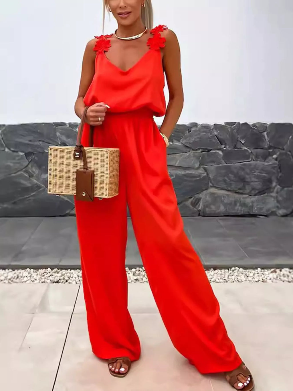 Floral Applique V-Neck Wide-Leg Red Jumpsuit with floral strap accents; model carries a wicker bag.