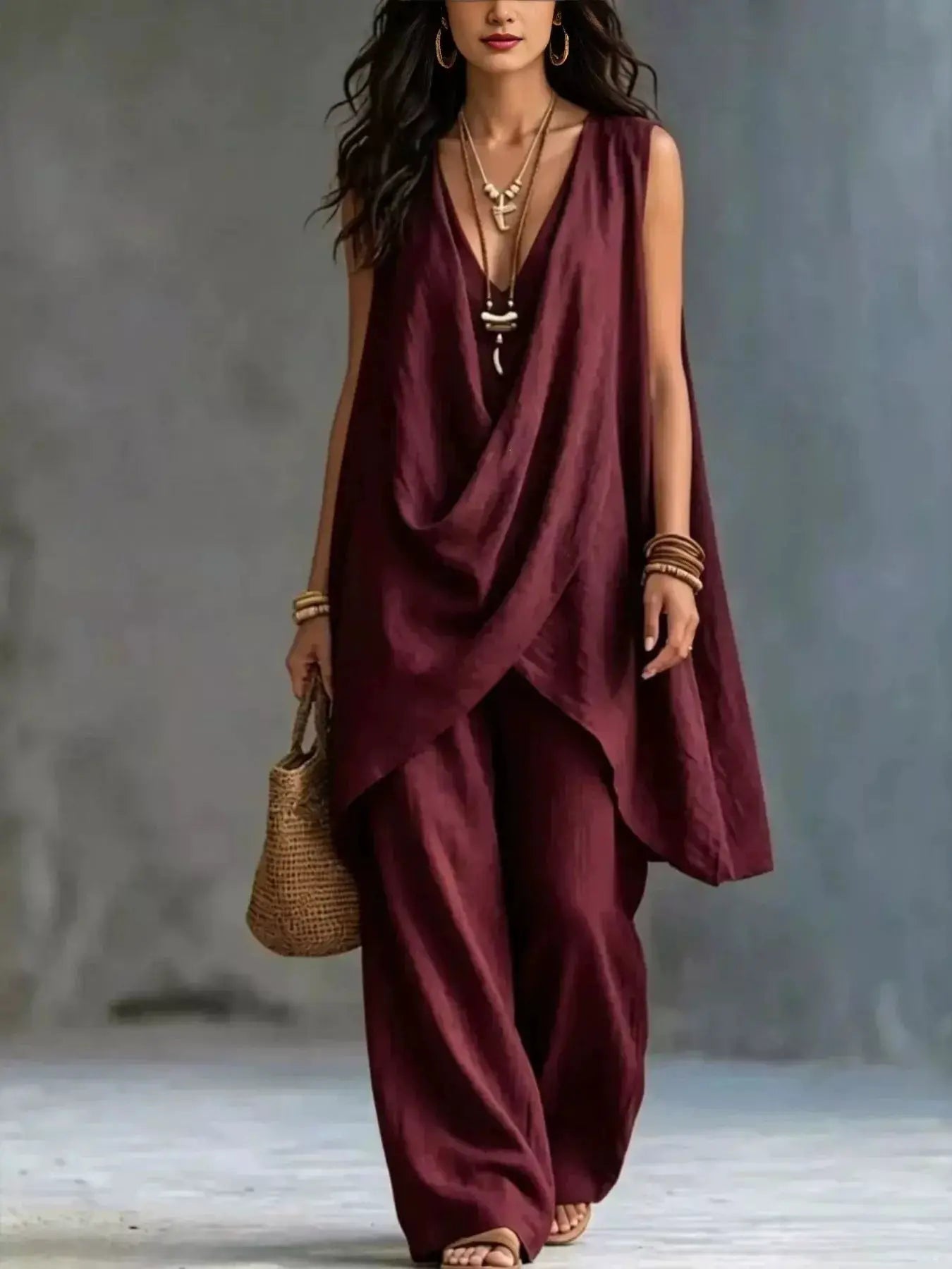Sleeveless burgundy asymmetrical top and wide-leg pants set, model with layered necklaces and bangles