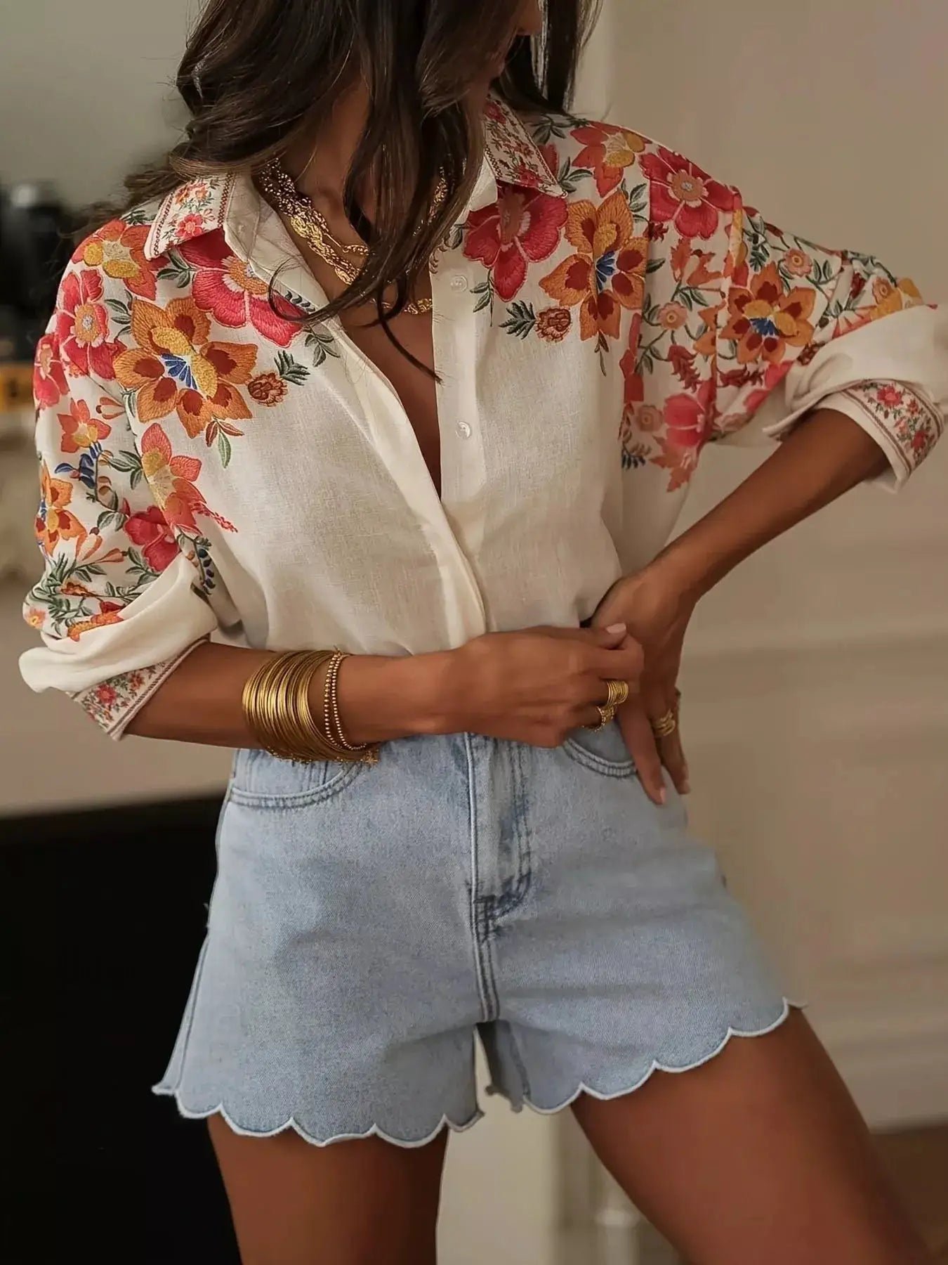 Floral print button-up top with white base and vibrant blossoms on sleeves, rolled cuffs.