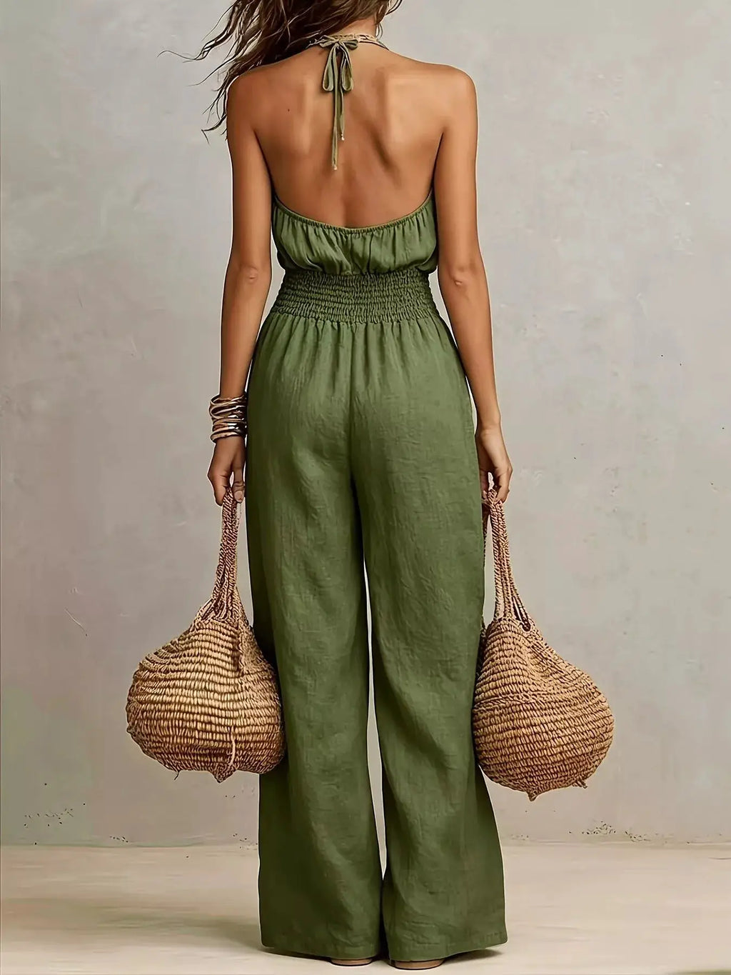 Smocked halter-neck wide-leg jumpsuit in olive green, by Trendsi; shown with two woven straw bags