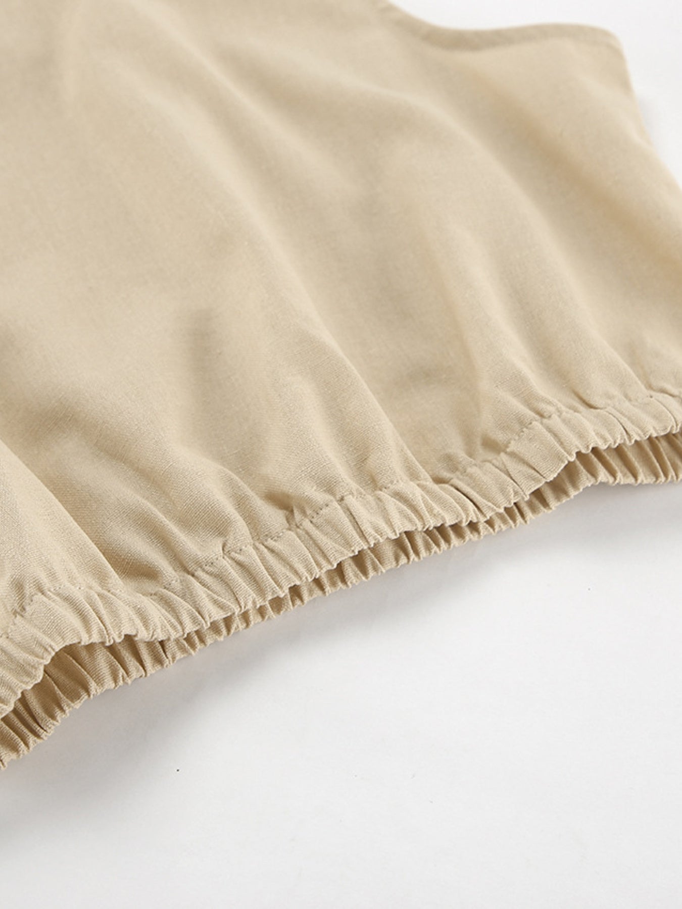 Sleeveless crop top and slit pants set in beige; close-up of soft knit fabric with elastic hem.