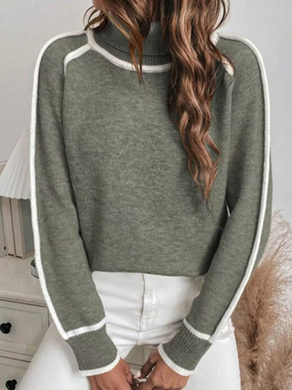 Military green turtleneck sweater styled with white pants, front view